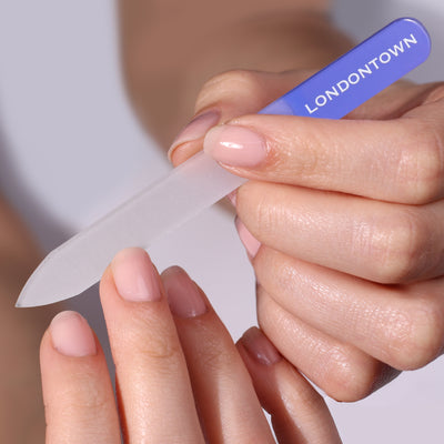 A person effortlessly uses the LONDONTOWN Glass Nail File - Lilac to shape their fingernails without causing any damage.
