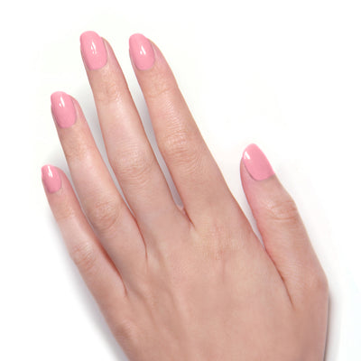 A hand with neatly manicured nails, adorned with LONDONTOWN's Queen of Hearts Galentines Day Set in glossy pink, rests on a white surface.