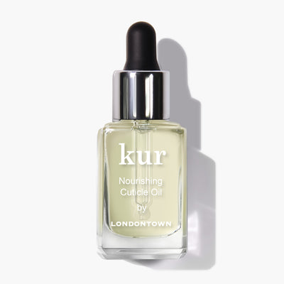 A clear bottle of LONDONTOWN's Nourishing Cuticle Oil with a dropper cap, containing light yellow oil enriched with multi-correctional plant extracts for ultimate nail restoration.