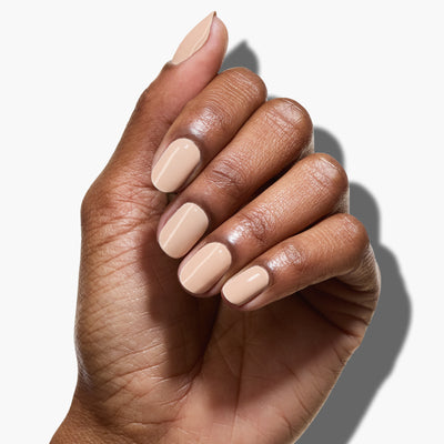 A hand with neatly manicured nails painted in Dusk, a neutral nude beige shade by LONDONTOWN, against a white background.