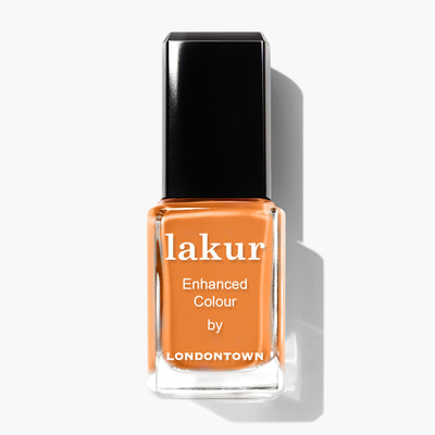 A bottle of LONDONTOWN's Heat Wave Lakur Enhanced Colour nail polish, featuring a burnt orange shade, with a black cap and white text on the label.
