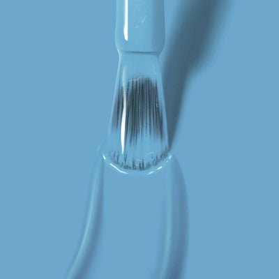 A close-up of a paintbrush coated in Hot Spring by LONDONTOWN against a serene blue background.
