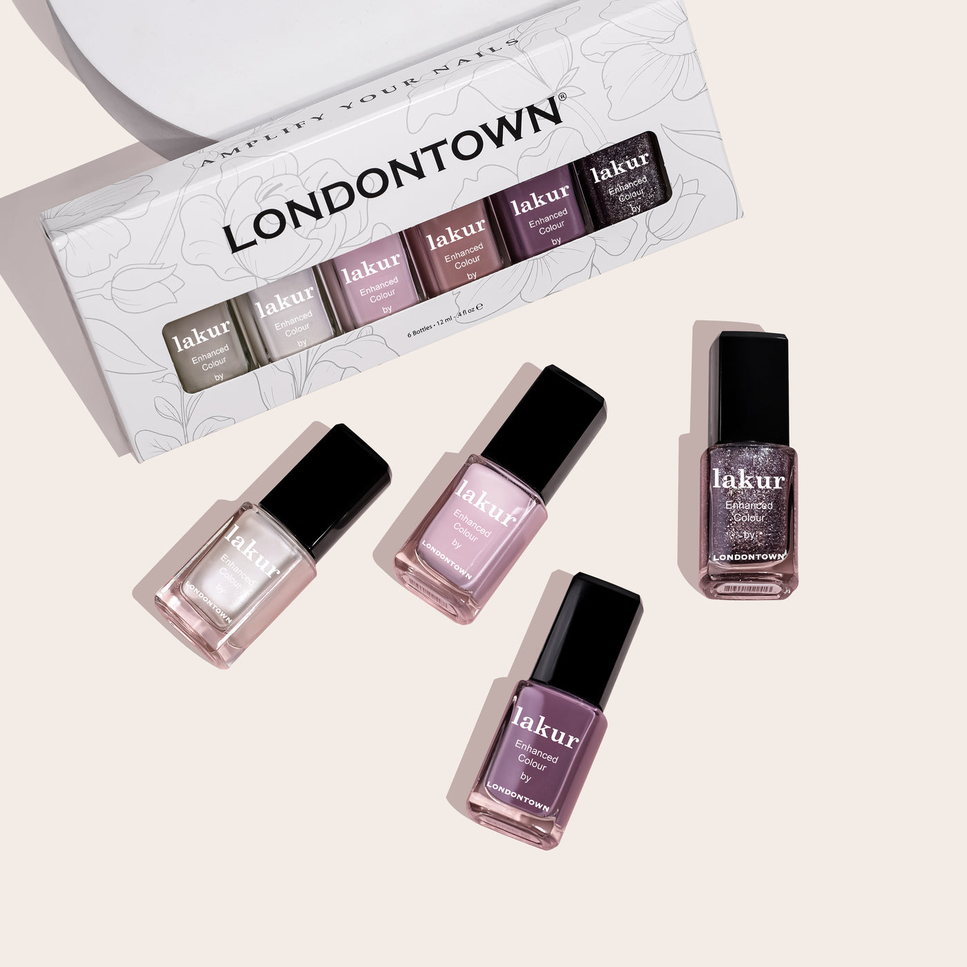 Five bottles of LONDONTOWN's I Do! Bridal Set nail polish in pink and purple shades are displayed, with one bottle each placed outside the open packaging adorned with a floral design. Create memorable moments with a perfect manicure using these captivating colors.