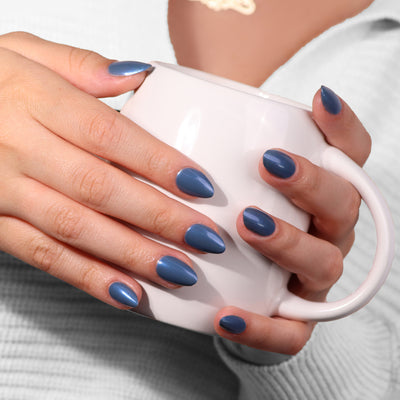 Hands with sporty Blue Diamond nail polish by LONDONTOWN holding a white mug.