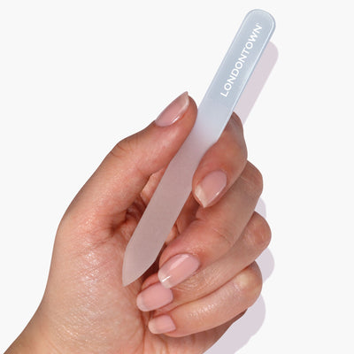 Close-up of a hand holding the Glass Nail File - Milky from LONDONTOWN, showcasing manicured nails and highlighting an effortless and damage-free nail filing experience.