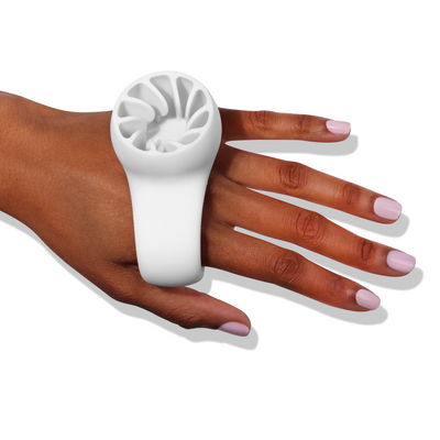 A hand with painted nails wears the LONDONTOWN Bottle Service Polish Holder, a white silicone ring-shaped accessory, on its fingers, making easy manicures or mess-free pedicures a breeze.