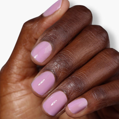 A hand with neatly manicured nails painted in LONDONTOWN's Perfecting Nail Veil #9, a light lavender shade, against a white background, showcasing the hint of color with care and precision.