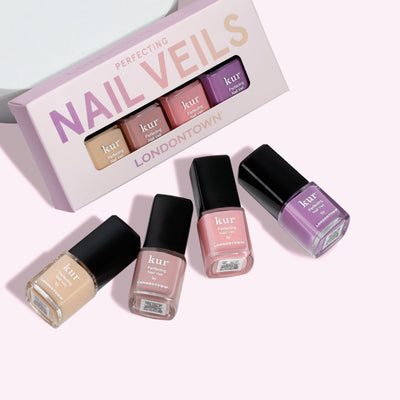 The Perfecting Nail Veil Mini Set by LONDONTOWN includes four nail polishes in sheer shades of beige, pale pink, medium pink, and lavender. Each bottle is elegantly displayed in front of the box for a sweet touch of perfection.