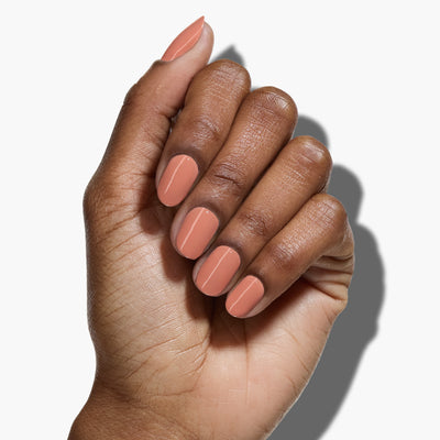 A hand with a medium skin tone is shown with neatly manicured nails painted in LONDONTOWN's muted, clay-colored polish, Savanna.