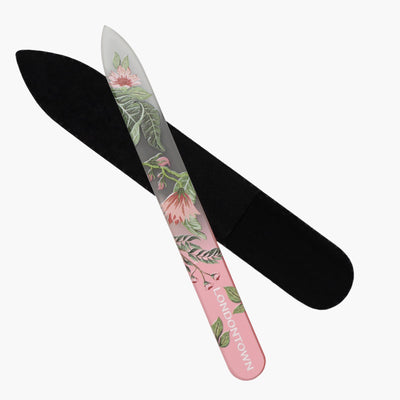 A floral-patterned glass nail file named "Glass Nail File - Safara" by LONDONTOWN is partly inserted into a black protective sleeve, making nail filing effortless and damage-free.
