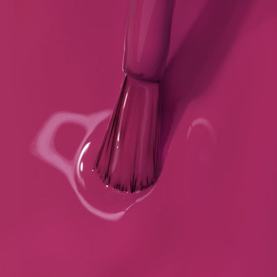 Close-up of a brush applying Teeny 'Kini nail polish from LONDONTOWN on a smooth surface, showcasing the texture and shine of the bright pink hue.