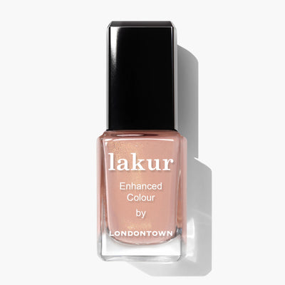 A bottle of lakur Enhanced Colour nail polish by LONDONTOWN, featuring Amber Lights (Professional) with a sunset-inspired nude pink shade and a black cap.