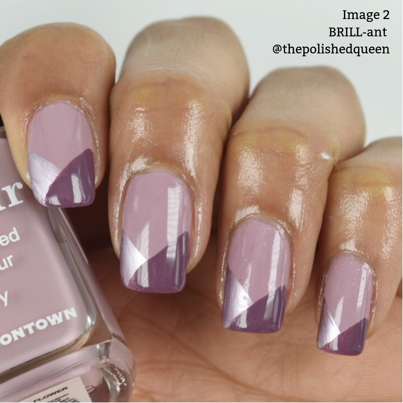 A hand with manicured nails in a geometric design, featuring shades of purple and lavender, accented with metallic-rose nail polish. The person is holding a bottle of 16+ Free, vegan cruelty-free nail polish from LONDONTOWN labeled "BRILL-ant." Text on the upper right reads "Image 2 BRILL-ant @thepolishedqueen.