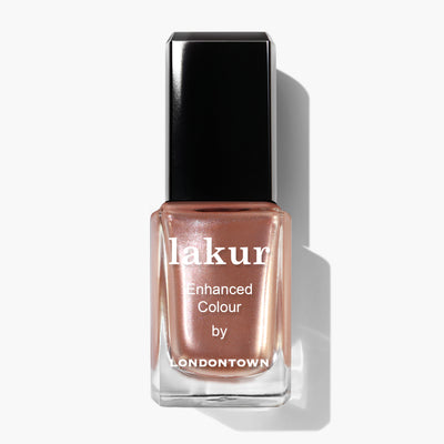 A bottle of LONDONTOWN Boozy Brunch nail polish with a coppery rose gold shimmer and a black cap.