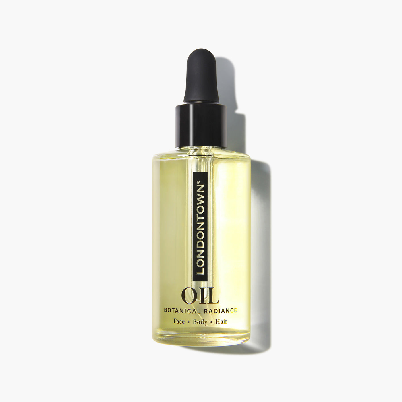 A clear glass dropper bottle labeled "LONDONTOWN Botanical Radiance Oil," containing a light yellow, multi-purpose oil for face, body, and hair, situated against a white background.