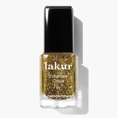 A bottle of LONDONTOWN Britannia nail polish in a sparkling gold color with text "lakur Enhanced Colour by LONDONTOWN" on the front of the bottle. This vegan, cruelty-free polish adds a luxurious gold accent to your nails.