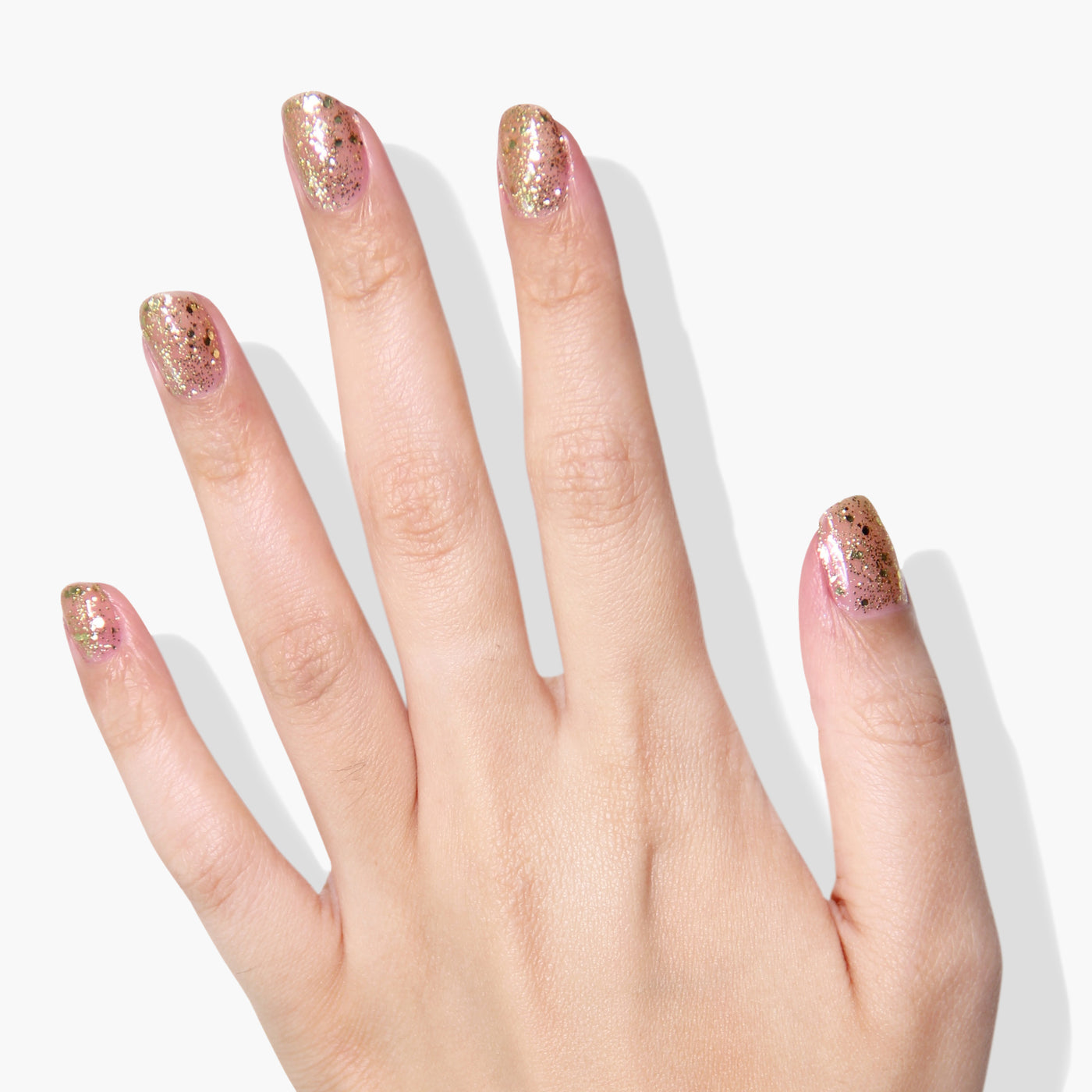 A hand with manicured nails featuring a light pink base using LONDONTOWN's Britannia and gold glitter accents on a white background.