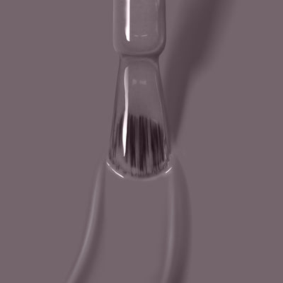 A close-up image of a nail polish brush applying LONDONTOWN's Cashmere, a vegan and cruelty-free grayish-purple polish, offering superior one coat coverage on a slightly blurred background.