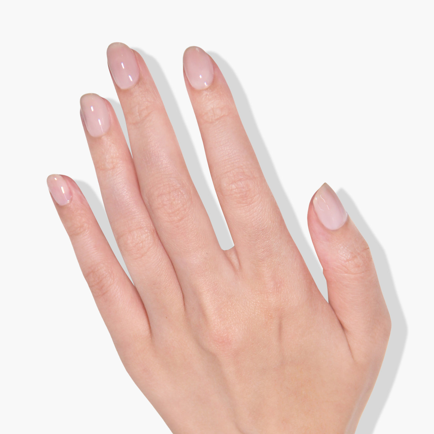 A hand with neatly manicured nails painted in LONDONTOWN's Cheerio, a sheer neutral pink shade, shown against a white background.