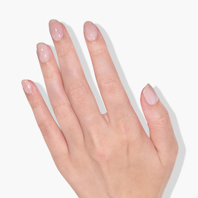 A hand with neatly manicured nails painted in LONDONTOWN's Cheerio, a sheer neutral pink shade, shown against a white background.
