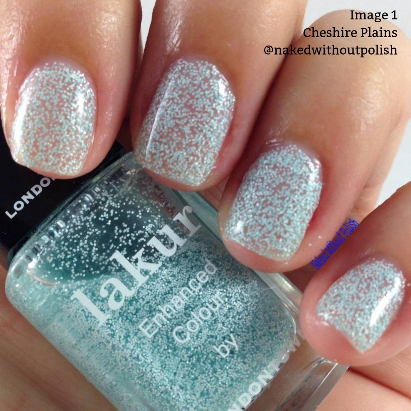 A close-up of fingers with nails painted in LONDONTOWN's "Cheshire Plains" mint green polish with white speckles, adorned with a clear sparkle top coat, holding a bottle of Lakur's "Enhanced Colour" cruelty-free nail polish in the same shade.