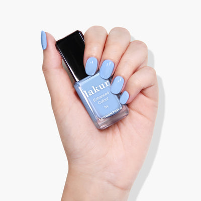 A hand holding a bottle of LONDONTOWN nail polish in Chuffed to Bits, with nails painted to match.
