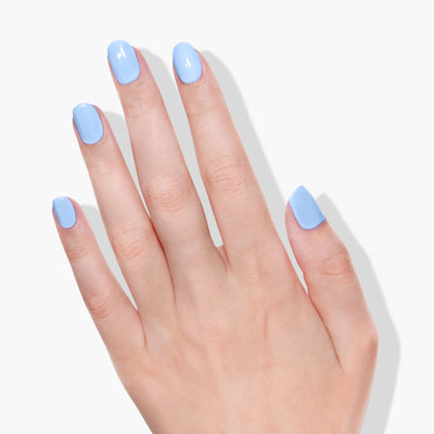 A hand with neatly manicured nails is painted in Chuffed to Bits (Professional), a periwinkle crème blue shade using vegan cruelty-free nail polish by LONDONTOWN, shown against a plain white background.