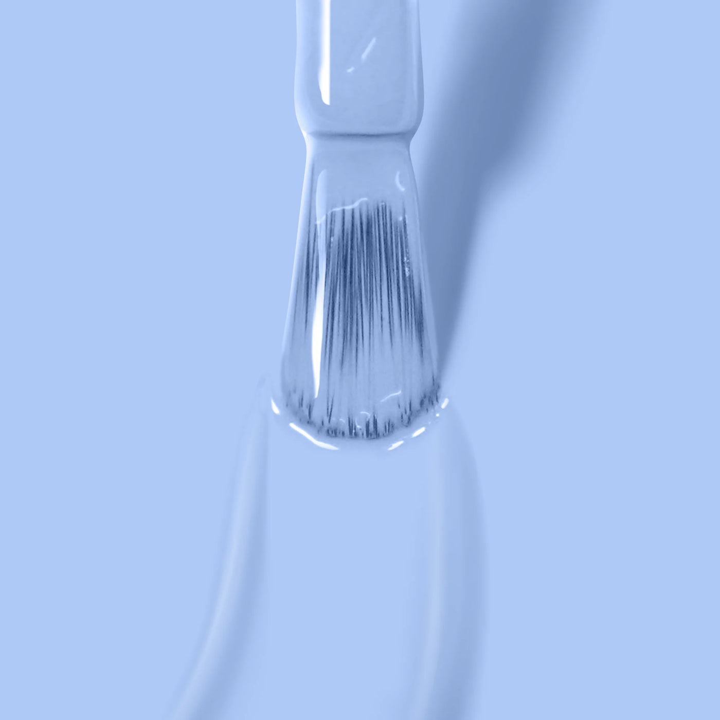 Close-up of a paintbrush with Chuffed to Bits (Professional) by LONDONTOWN paint in light blue, periwinkle crème blue. The bristles are saturated with the paint, and a drip is forming at the tip. The background is uniformly light blue.