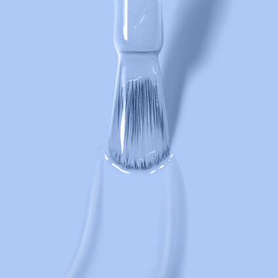 Close-up of a paintbrush bristles dipped in Chuffed to Bits by LONDONTOWN against a light blue background.