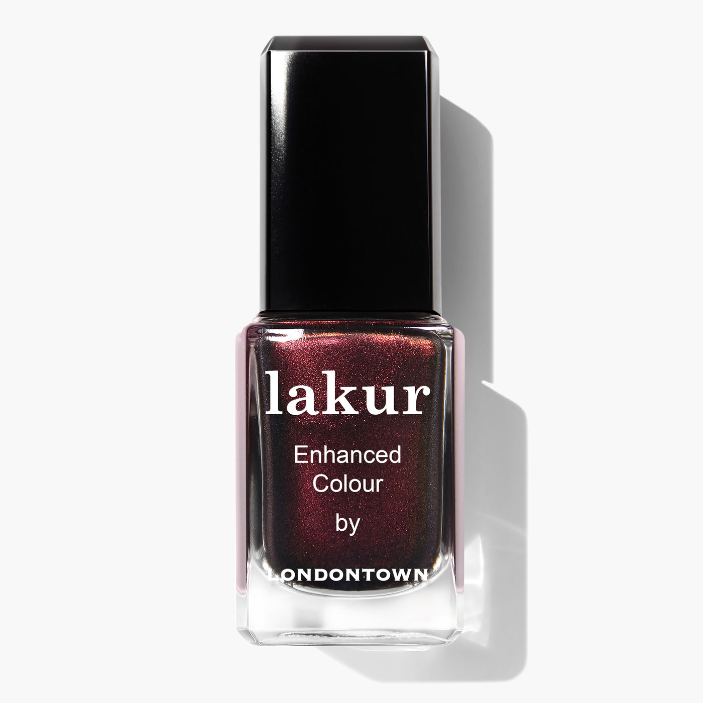 A bottle of LONDONTOWN's Cockney Glam Lakur enhanced color nail lacquer features a dark, shimmering, red-toned metallic crème. This PETA certified, vegan cruelty-free polish ensures an ethical and glamorous manicure.