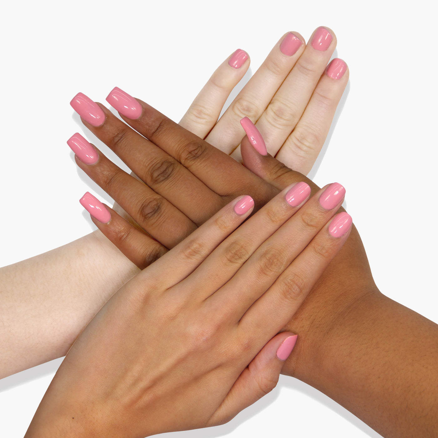 Three pairs of hands with different skin tones are shown with LONDONTOWN's vegan, cruelty-free, Desert Flower nail polish in salmon pink, overlapping each other against a white background.