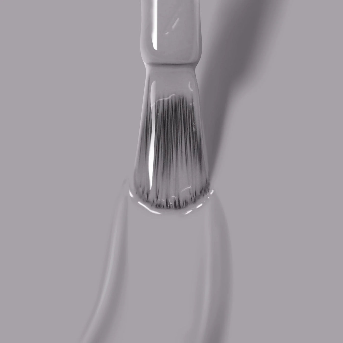 Close-up image of a paintbrush applying a smooth layer of sleek grey paint on a surface, with bristles partially coated and visible brushstrokes, resembling the even application of LONDONTOWN's Earl Grey (Professional) cruelty-free vegan nail polish.