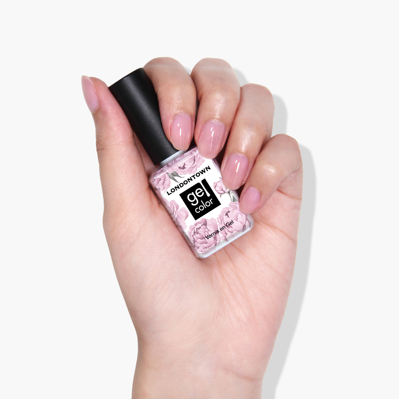 A hand with painted pink nails holding a bottle of LONDONTOWN’s Fairy Charming gel color, showcasing its super pigmented formula.