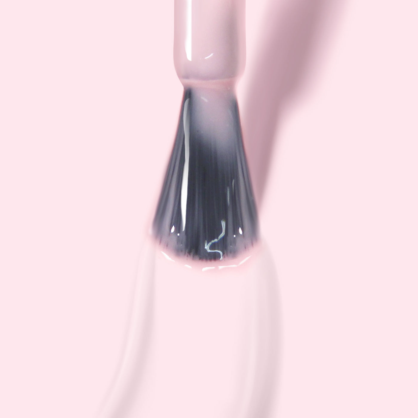 A close-up image of a nail polish brush with LONDONTOWN's Fairy Charming gel color in light pink against a pale pink background, showcasing its super pigmented formula.