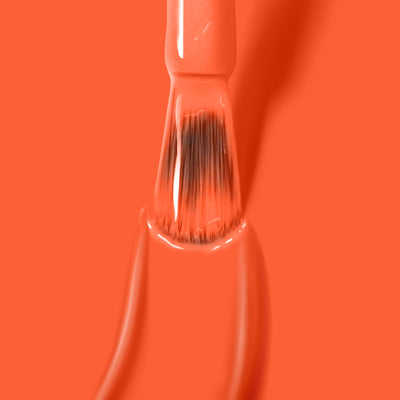 A brush dipped in vibrant LONDONTOWN's Flashback gel color, partially submerged in a pool of neon orange nail polish.