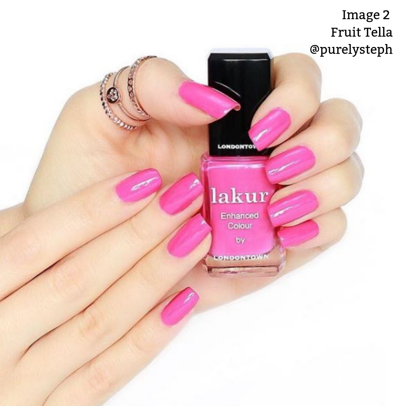 Two hands with manicured nails painted bright pink are holding a bottle of LONDONTOWN's Fruit Tella, part of their vegan and cruelty-free collection.