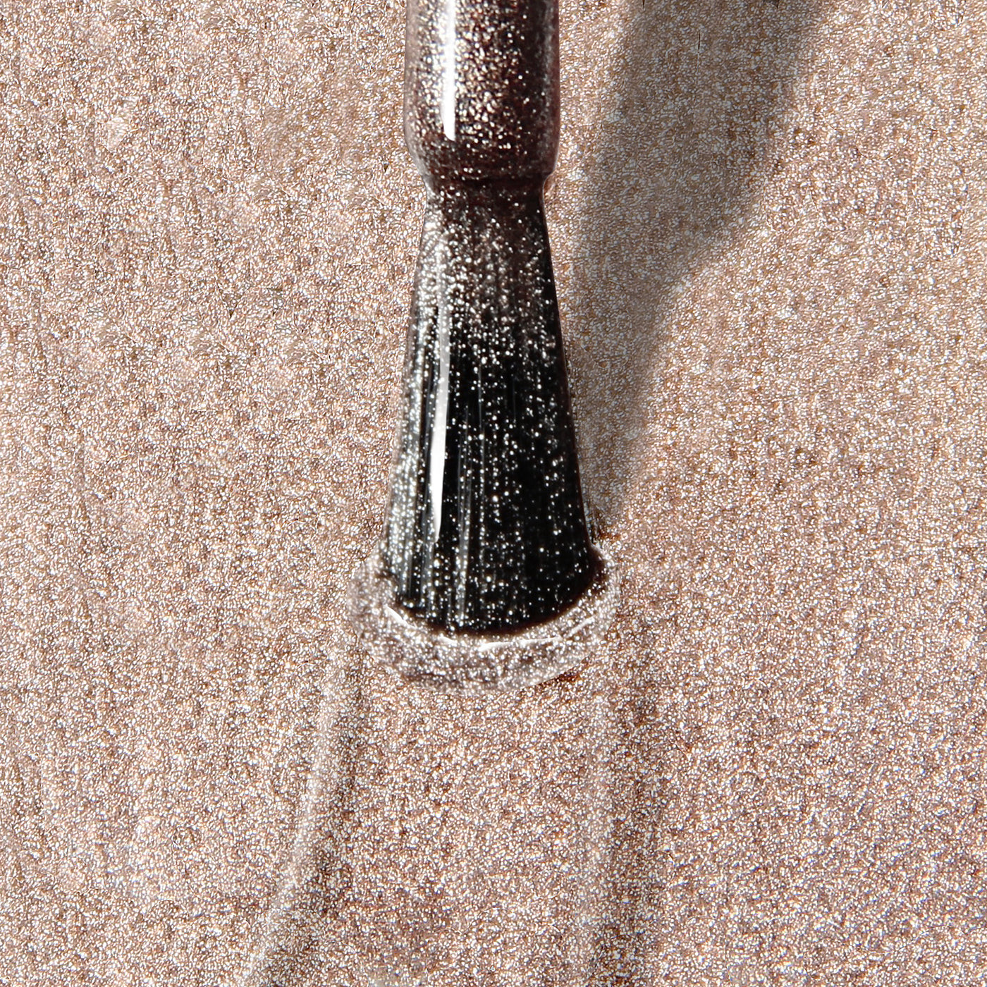 Close-up of a makeup brush spreading LONDONTOWN's Gilded, a shimmery, vegan, cruelty-free powder, across a surface, creating a sparkling effect.