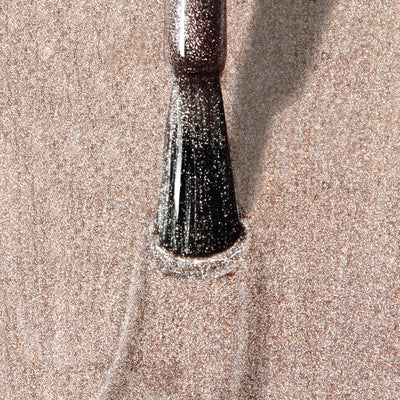 Close-up of a makeup brush spreading LONDONTOWN's Gilded, a shimmery, vegan, cruelty-free powder, across a surface, creating a sparkling effect.
