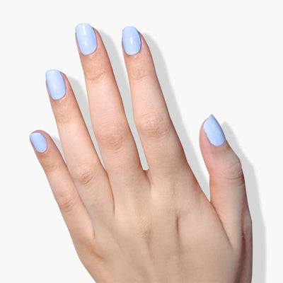 A hand with short, neatly manicured nails painted in a light blue, vegan nail polish called 'In the Clouds' by LONDONTOWN is shown against a white background.
