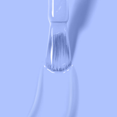 A close-up of a brush applying a smooth layer of light blue, vegan, and cruelty-free "In the Clouds" nail polish by LONDONTOWN on a surface.