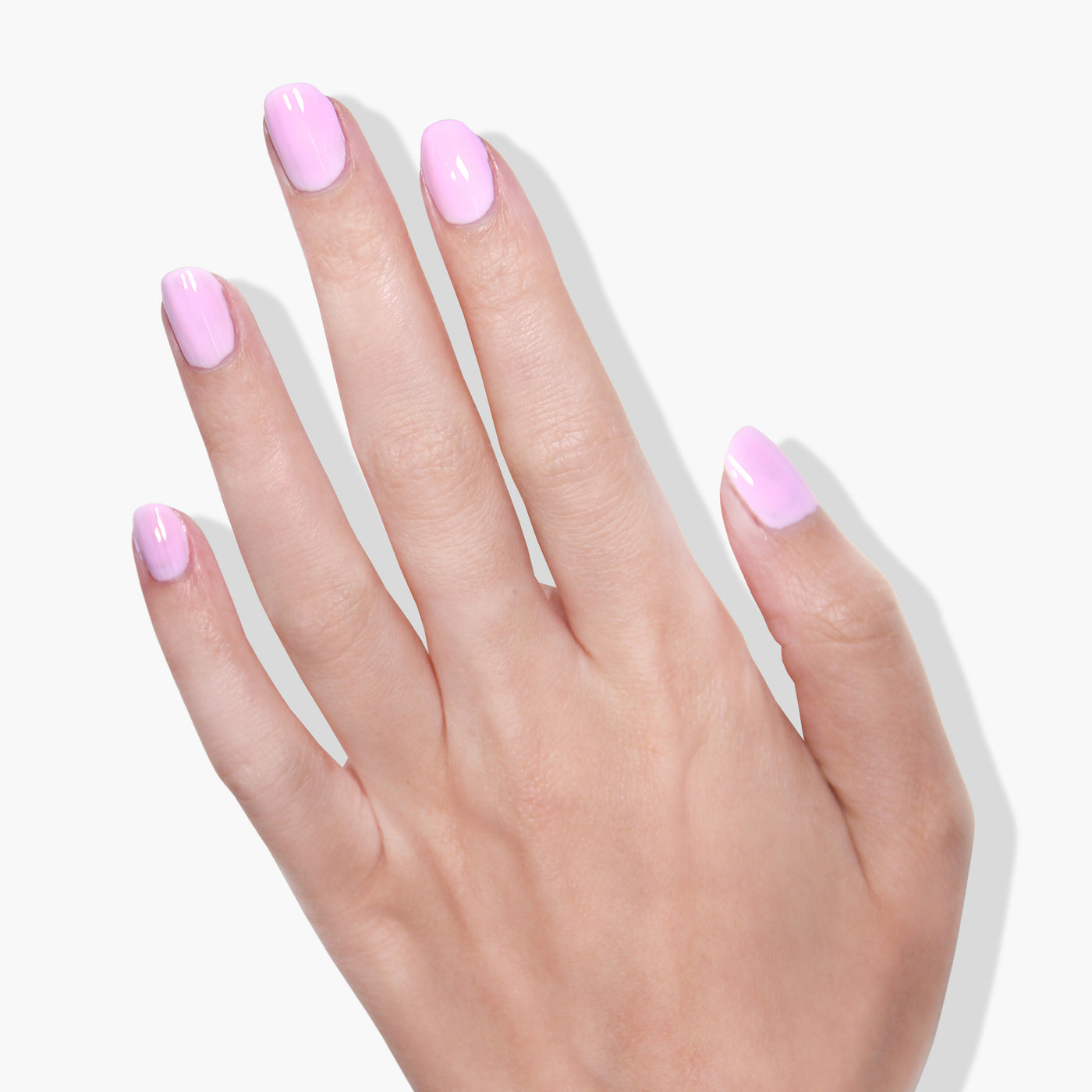 A hand with five fingers is shown against a white background. The nails, coated in LONDONTOWN's refreshing muted pink gel color, Lemonade Pop, gleam softly under the UV/LED light.