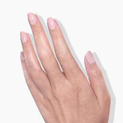 A close-up of a hand showcasing light pink Make Me Blush gel color manicured nails from LONDONTOWN against a white background.