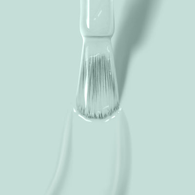 Close-up of a paintbrush with LONDONTOWN's Mint No Chip paint on its bristles, reminiscent of mint creme, against a light green background.