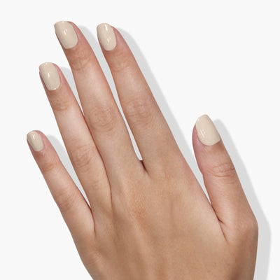 A close-up of a hand with neatly manicured nails painted in a light beige, French vanilla cream color using LONDONTOWN's Murray Me vegan, cruelty-free nail polish.