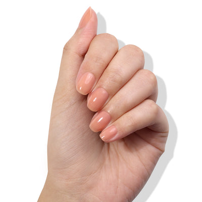 A hand with neatly manicured nails painted in the glossy nude shade of LONDONTOWN's Perfecting Nail Veil #5, shown against a plain white background, exemplifies the power-packed simplicity of meticulous nail care.