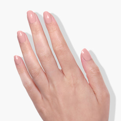 A hand with neatly manicured nails painted in the soft pink shade of Peach Please by LONDONTOWN, known for being vegan and cruelty-free, against a plain background.