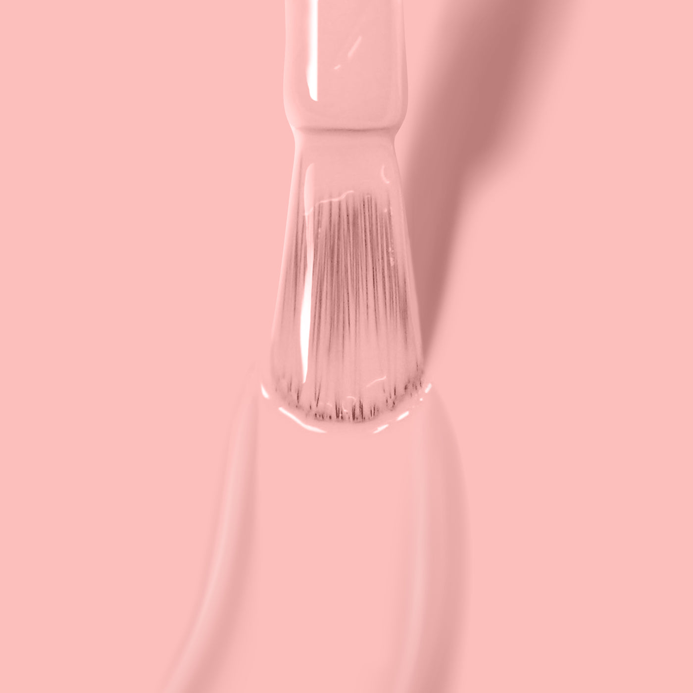 Close-up of a brush being dipped in LONDONTOWN's vegan cruelty-free Peach Please nail polish against a pink background.