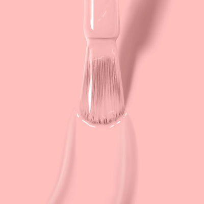 A brush is covered in Peach Please (Professional) by LONDONTOWN, with delicate pink paint strokes shown beneath it. The background is entirely pink, emphasizing the Vegan Cruelty-Free Nail Polish.