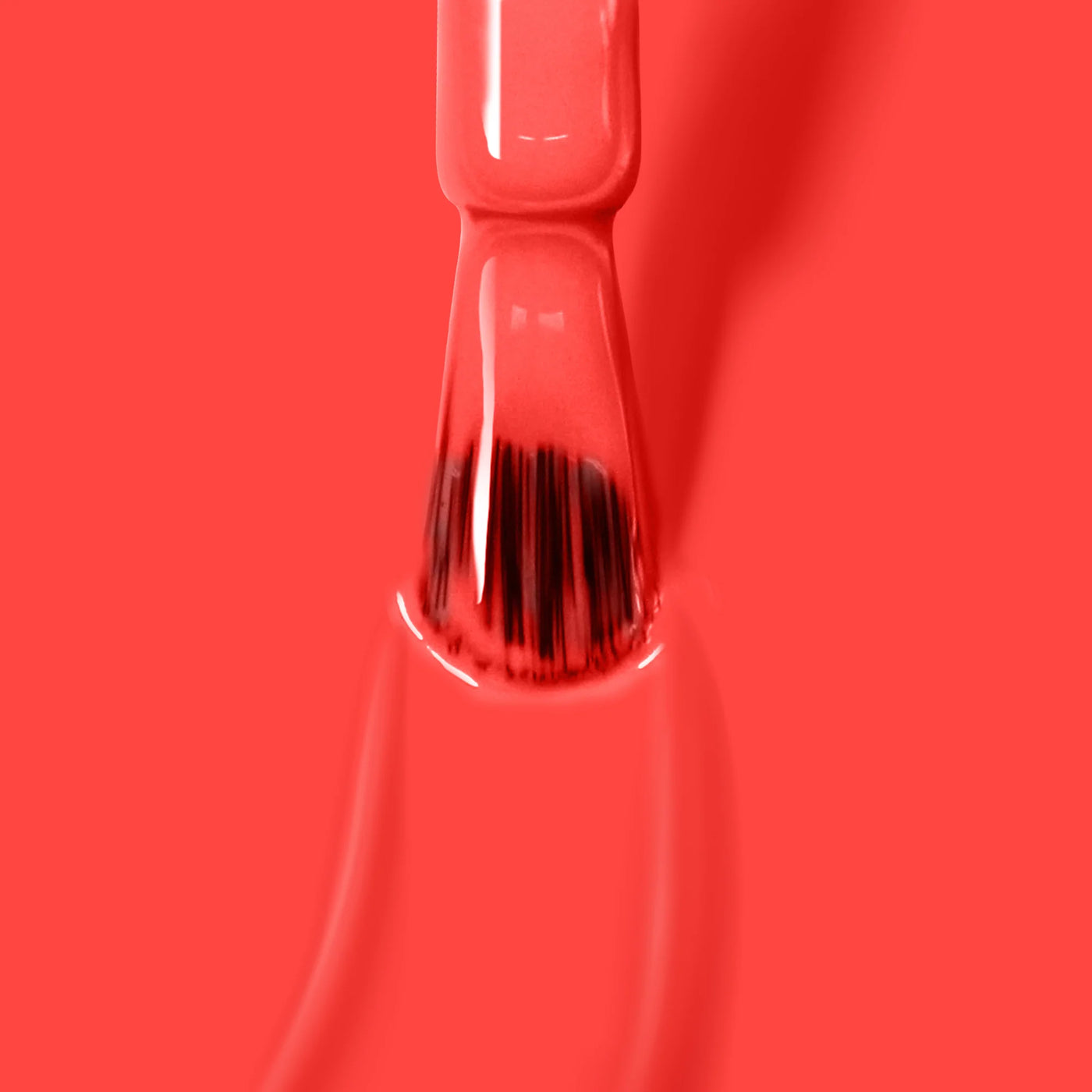 Close-up of a brush applying bright red nail polish from LONDONTOWN's collection, showcasing their ultra-bright blood orange crème "Piccadilly Square (Professional)" on a smooth surface.