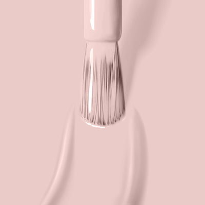 Close-up of a Plié (Professional) brush by LONDONTOWN applying light pink, cruelty-free, vegan nail polish on a smooth surface.